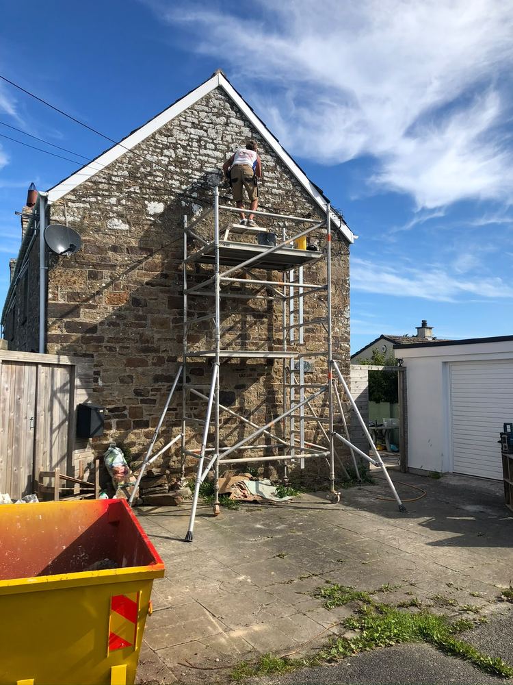 Stone gable end being repointed from scaffold