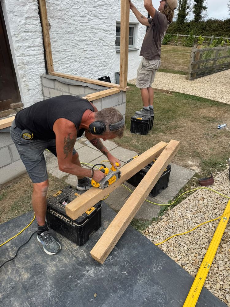 Dylan and Dave at work on site, cutting an oak beam